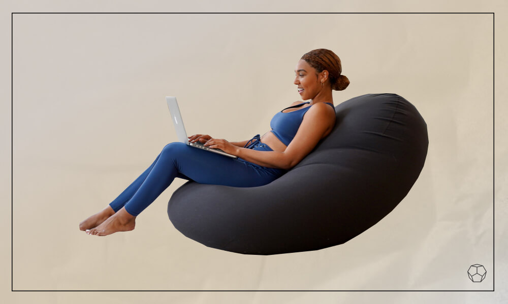 Woman laying grey bean bag chair with her laptop