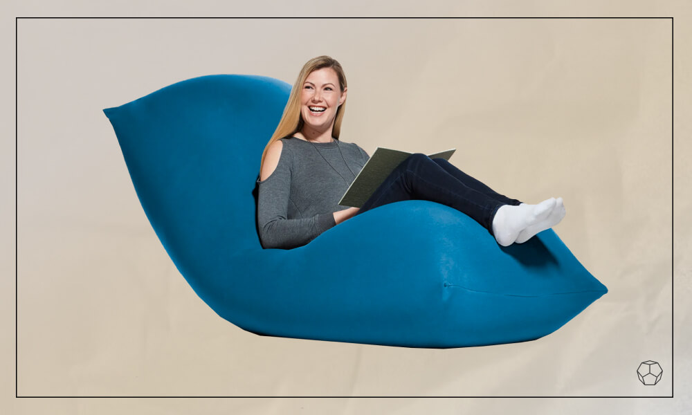 Woman sitting in a blue modern bean bag chair with her laptop