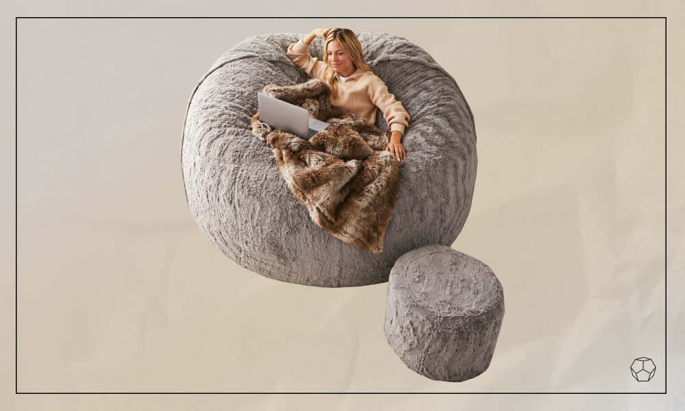 woman laying on a giant bean bag chair with her laptop