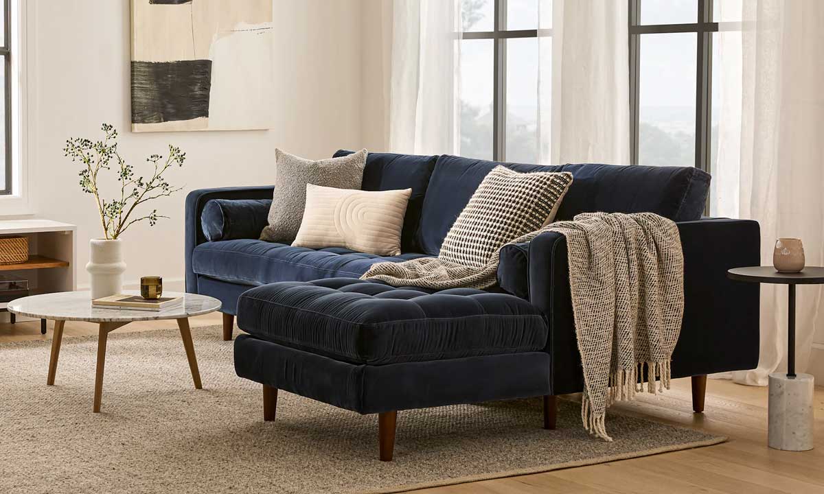 Dark blue Sectional Sofa in a bright living room with a light beige rug and a rounded coffee table