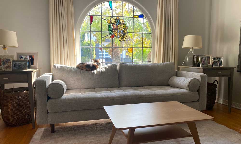 Grey Sofa in a living room with a squared coffee table, a light brown rug and warm furniture