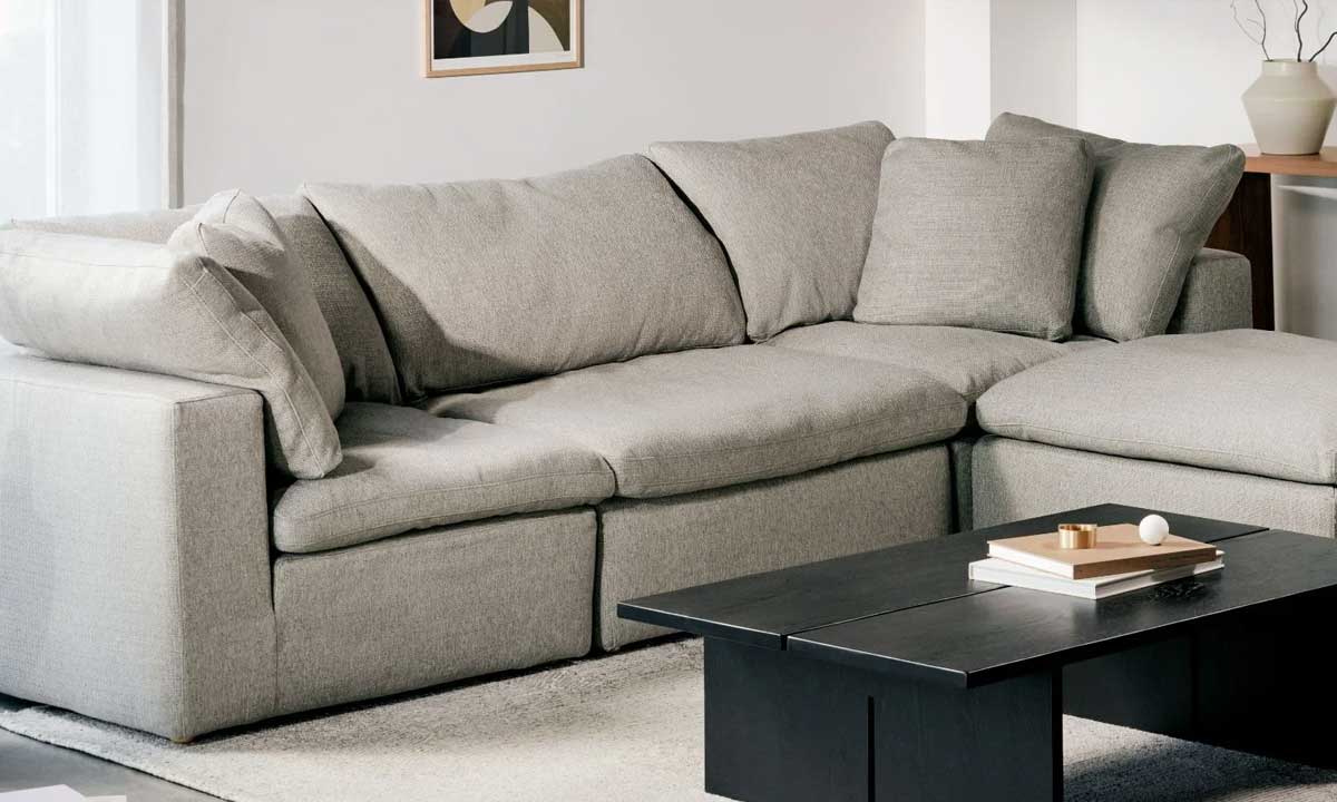 light grey L-shaped upholstered sofa in a bright living room with a black coffee table