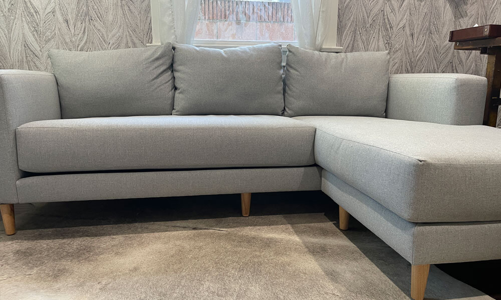 L-shaped grey upholstered sofa with light wooden legs