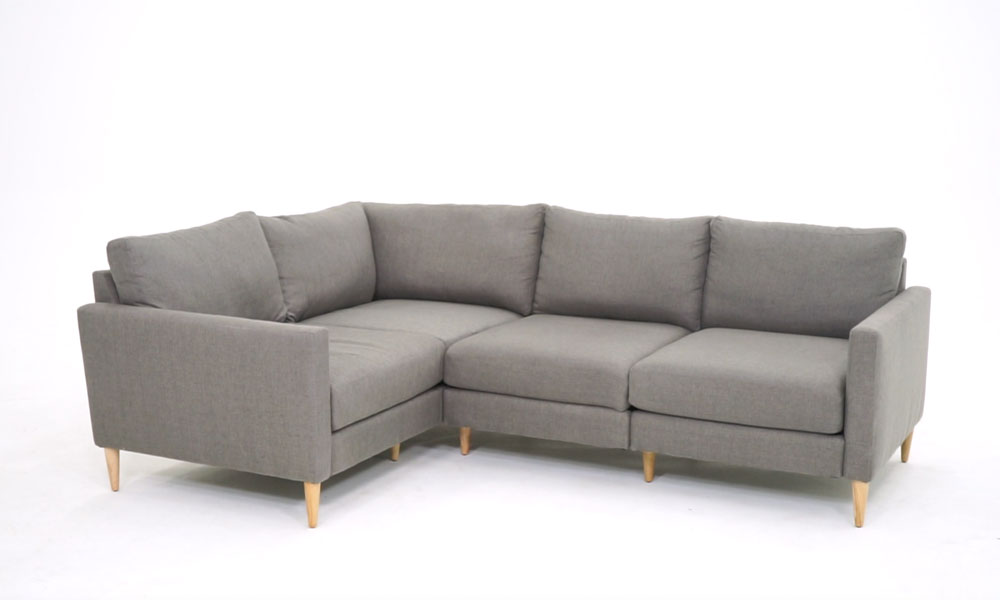 L-shaped grey upholstered sofa with light wooden legs