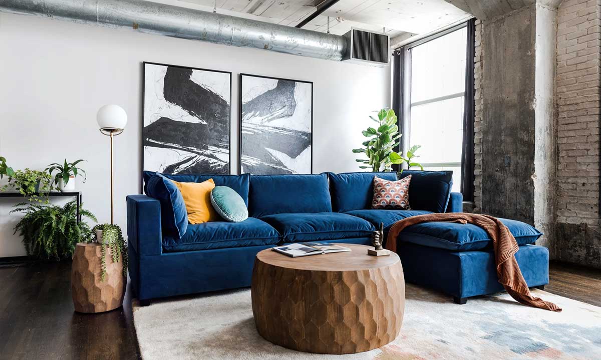 blue velvet sectional sofa with yellow and light blue throw pillows in a modern living room