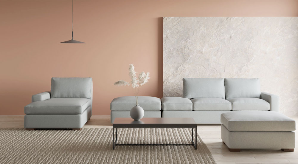 Minimalist living room featuring a light grey sofa, a matching ottoman and a corner chair