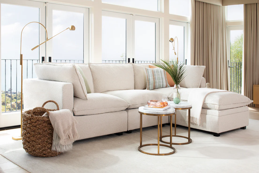 White upholstered sofa in a bright living room with white rug and two small round coffee tables