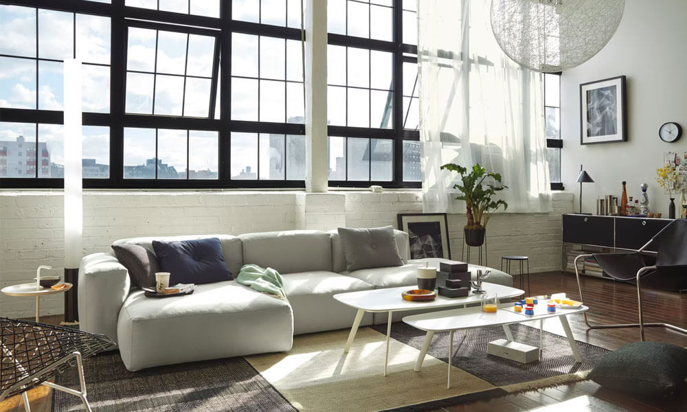 Grey upholstered Low Sectional near a large window in a bright living room