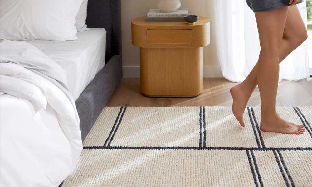 White rug with dark blue stripes in one side of a white bed