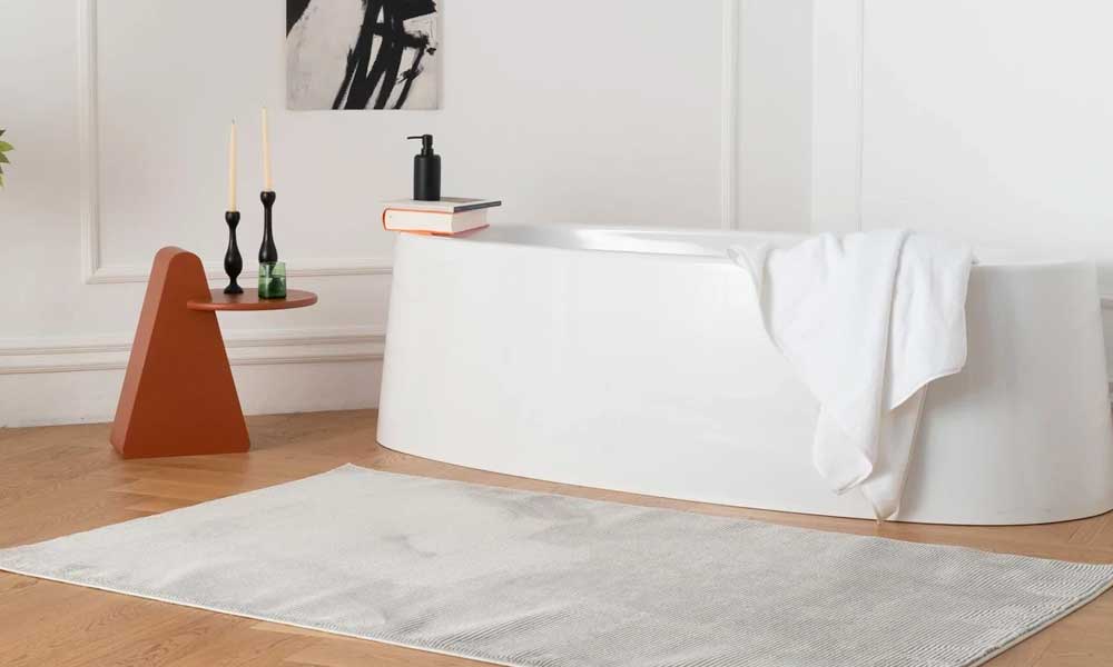 Grey washable rug near a bathtub