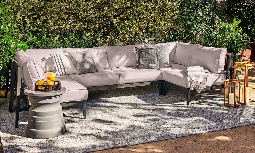 Outdoor Rug in Pebble Gray under an outdoor U-shaped grey sofa in a patio