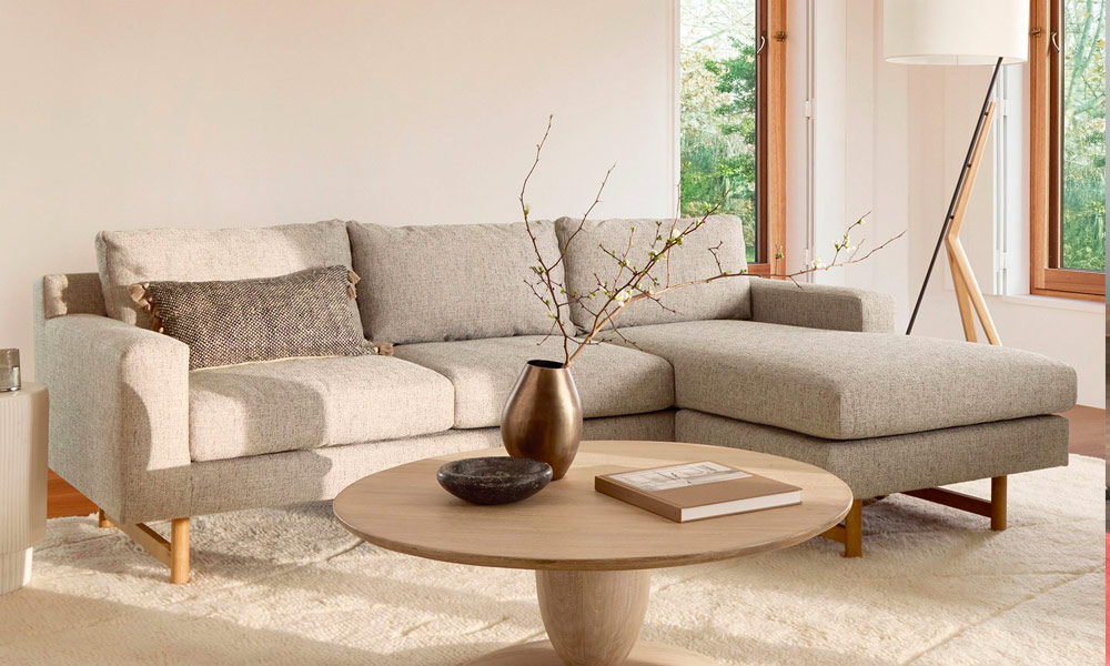 Beige Sectional Sofa with two grey lumbar throw pillows in a bright living space with a coffee table