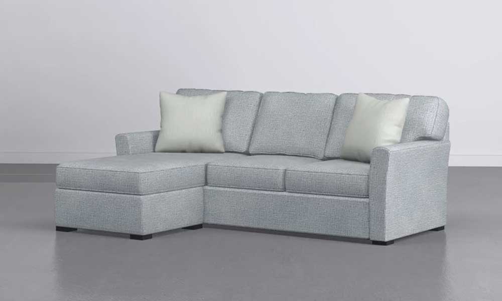 Light grey upholstered reversible sofa with a storage ottoman and large grey throw pillows