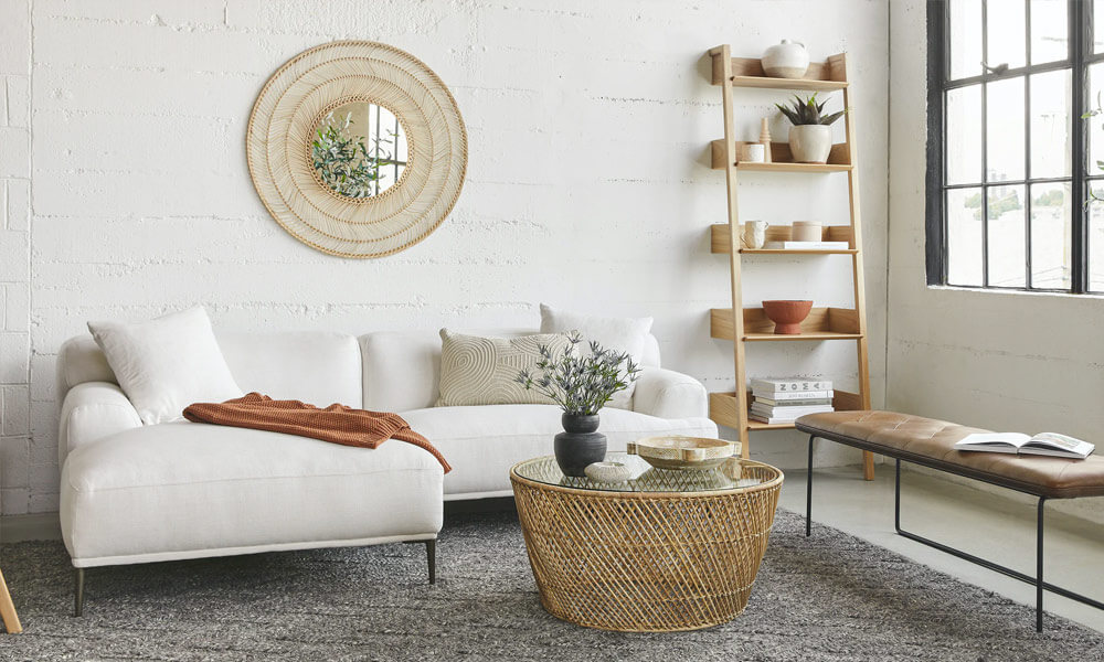 White sectional sofa with a brown blanket in it in a modern living space with a grey rug