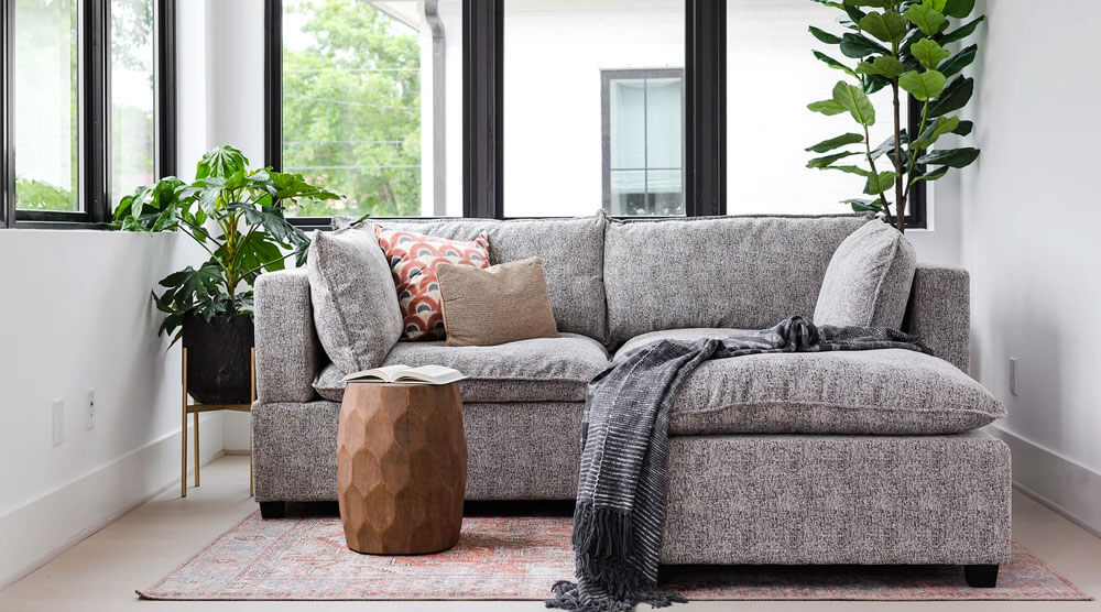 Grey upholstered Sectional Sofa with a set of throw pillows and a grey ottoman