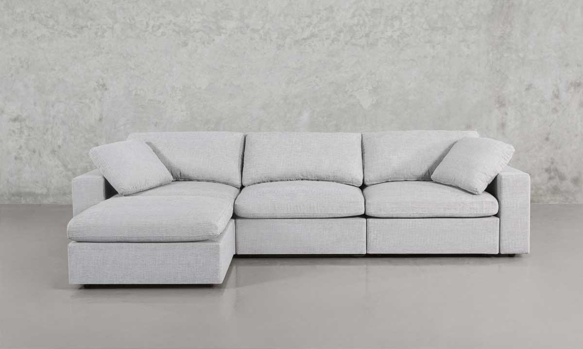L-shaped light grey upholstered sofa with two matching throw pillows