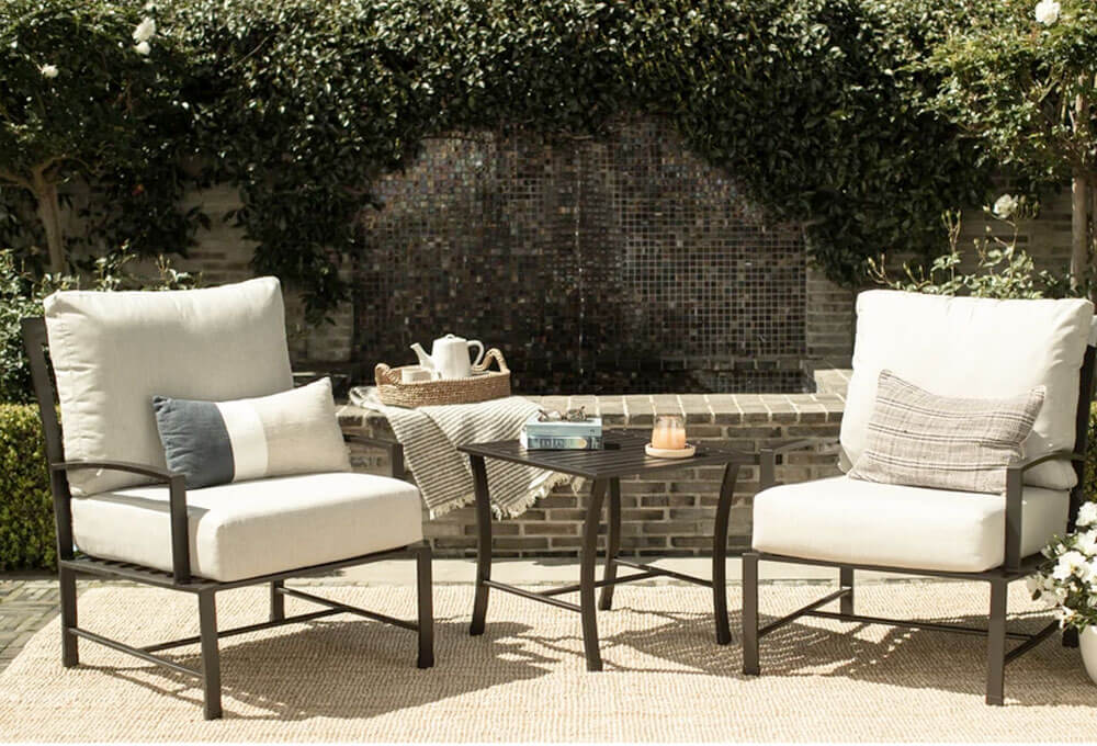 A patio furniture set featuring a table and two chairs with white cushions