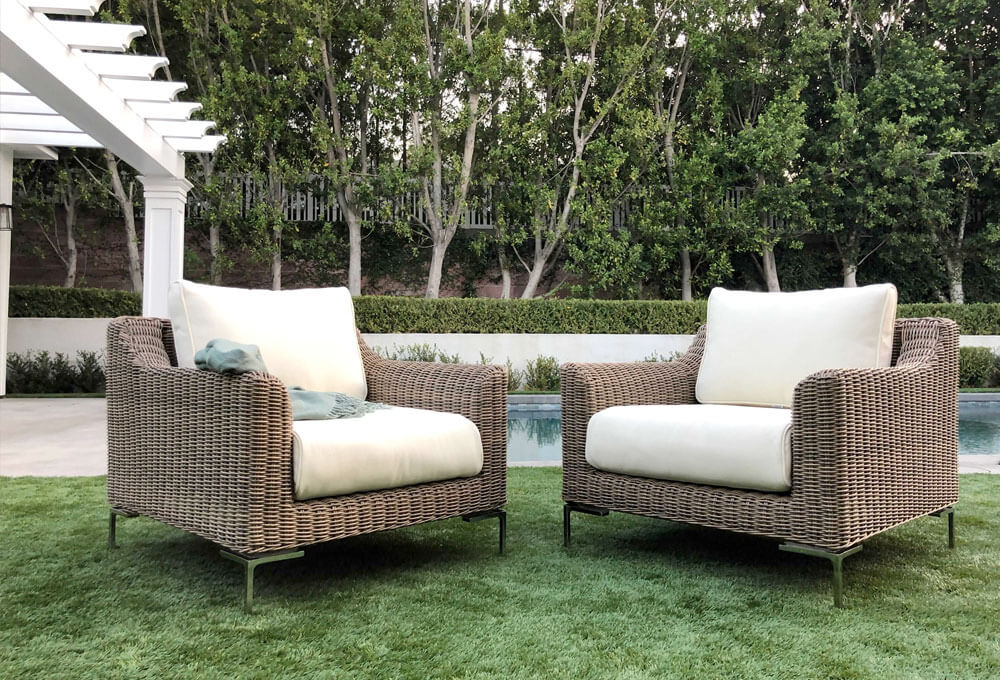 Outdoor seating with two wicker chairs on a lush green lawn