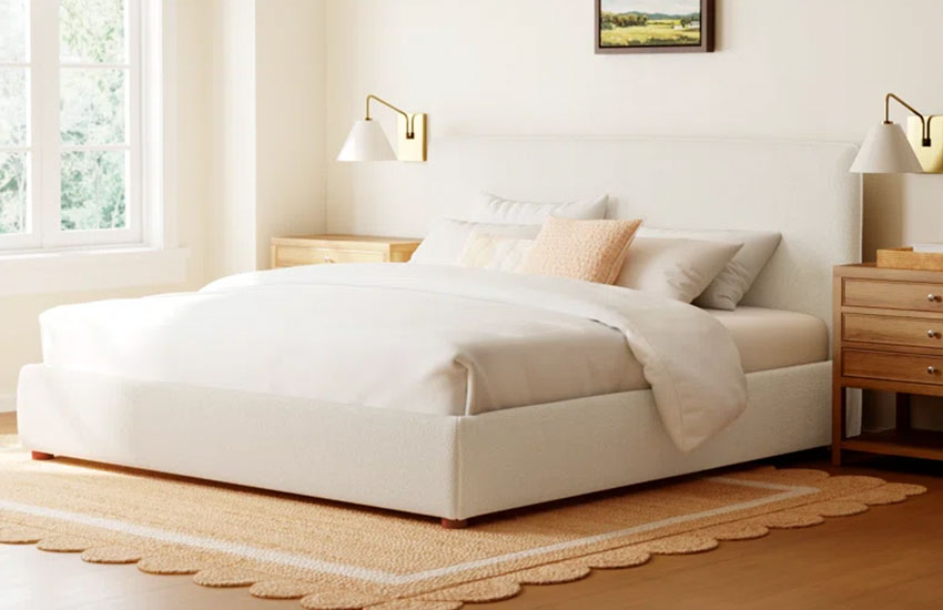 Cream Upholstered Bed with small wooden legs, a mattress with white sheets and five white pillows