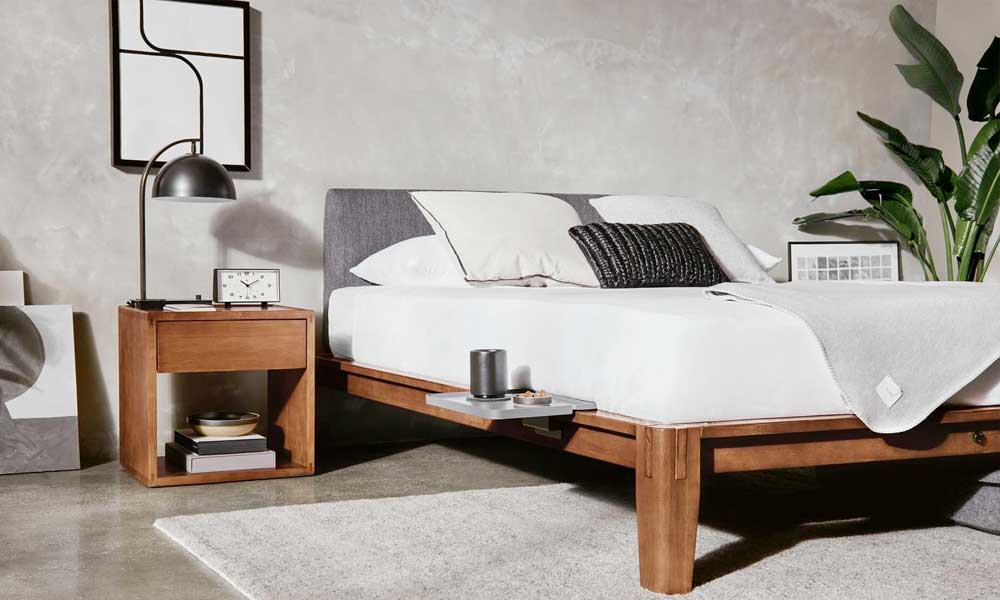 wooden platform bed with a bedside table in the left side and a mattress with bedding