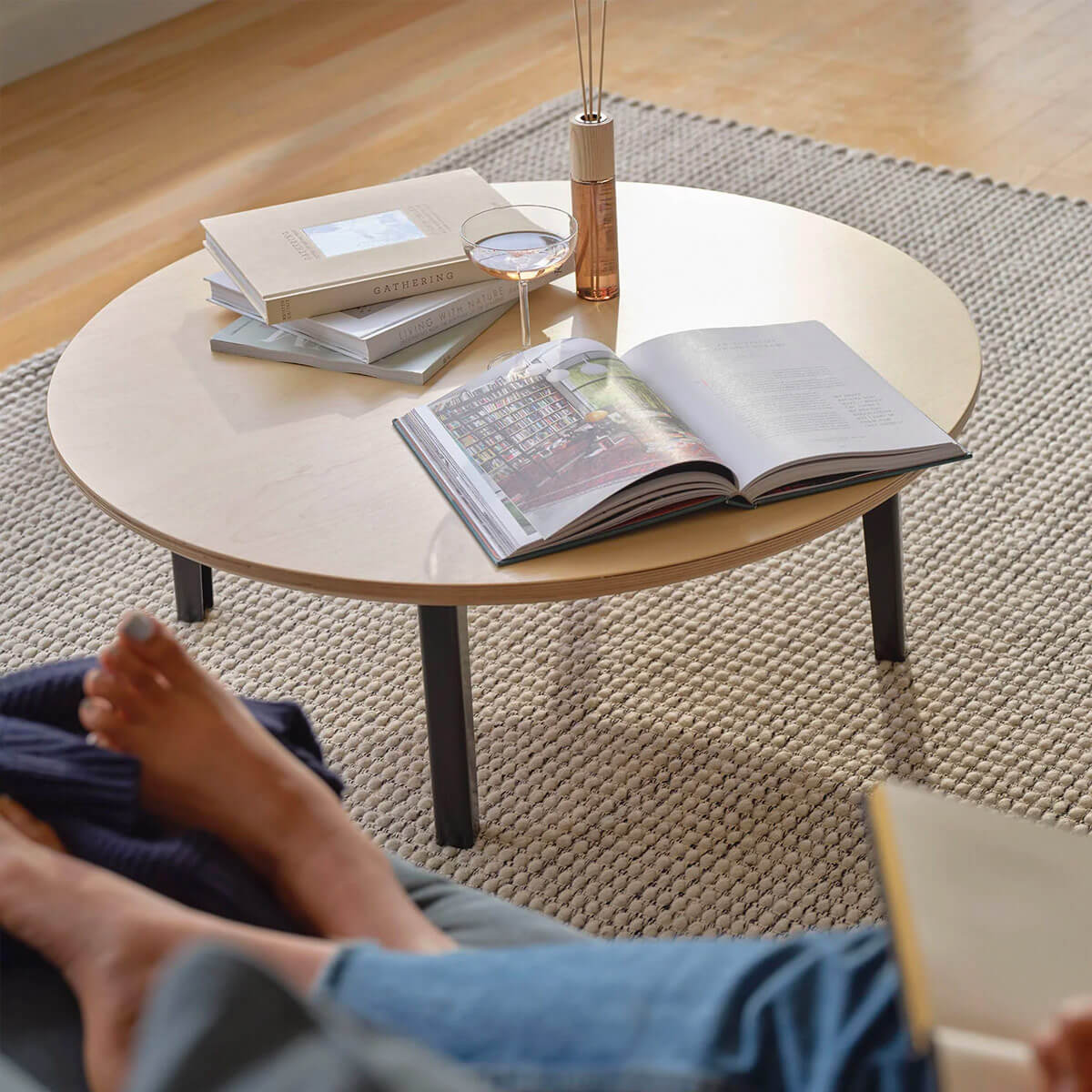 Round wooden Coffee Table placed on a light grey rug in a living room