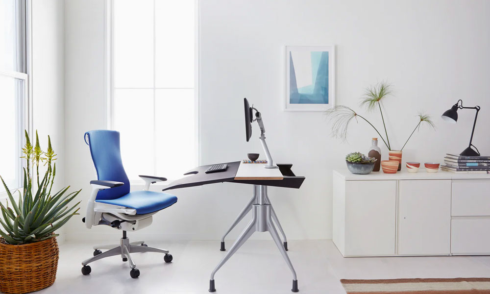 Ergonomic chair with white and grey frame and blue back and seat mesh in a desk room