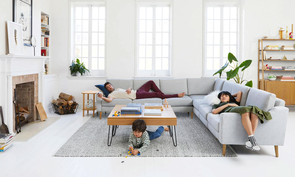 Family gathering in a living room with a sectional sofa, a large rug and a coffee table in the cente
