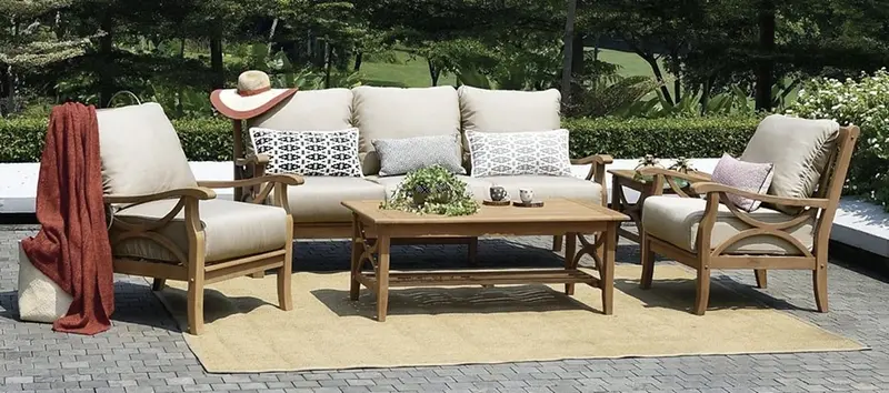 Wooden outdoor sofa set with light gray cushions on a patio in a sunny day