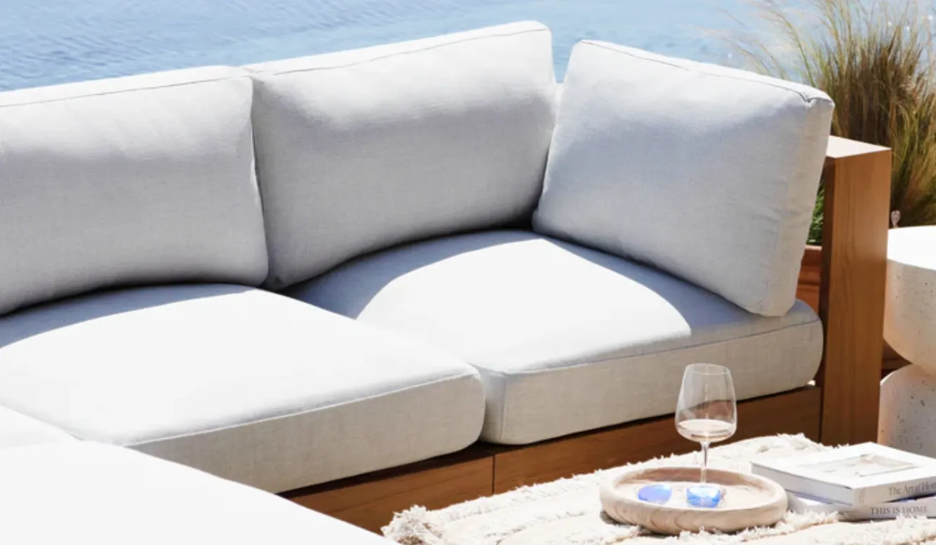 wooden frames sofa with white cushions near the ocean