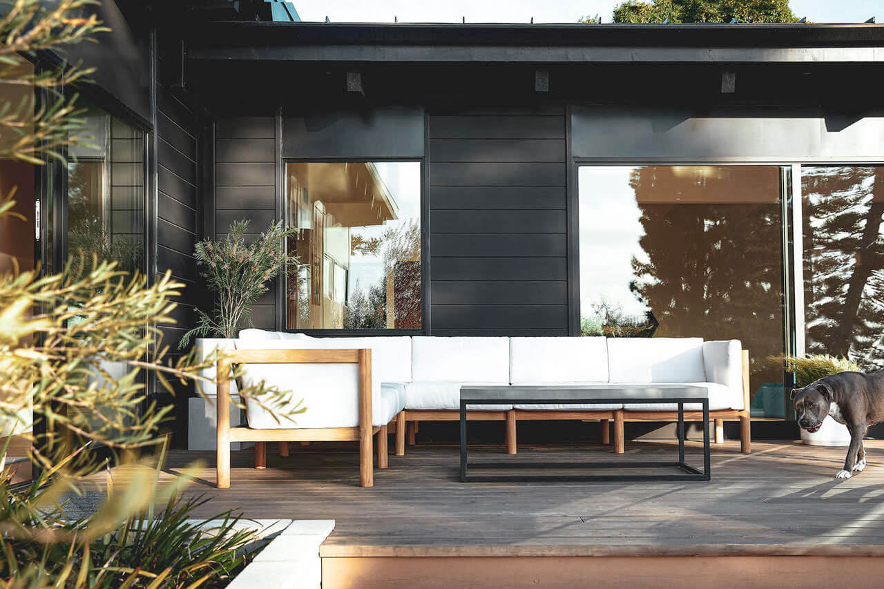 Wooden frame white sectional sofa in an utdoor space with a black aluminum coffee table