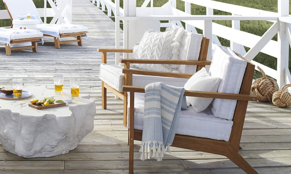 Two Teak Lounge Chairs with white cushions in an outdoor place on a sunny day