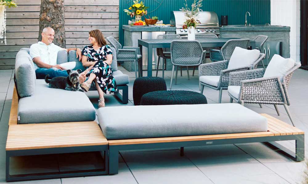 Wooden framed Outdoor Sectional with grey cushions and a couple relaxing on it in a patio