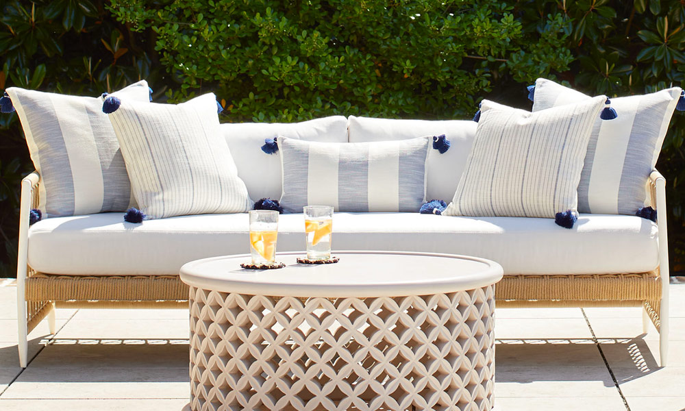 White outdoor Sofa with cushions with light blue stripes near a wooden crafted coffee table, outdoor
