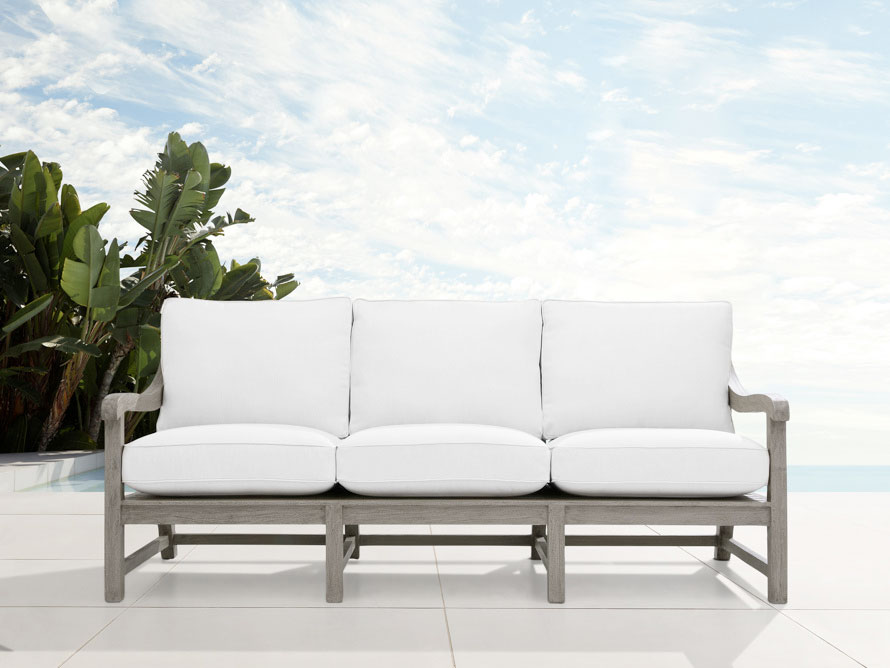 Grey framed outdoor sofa with white cushions in an outdoor space in a sunny day