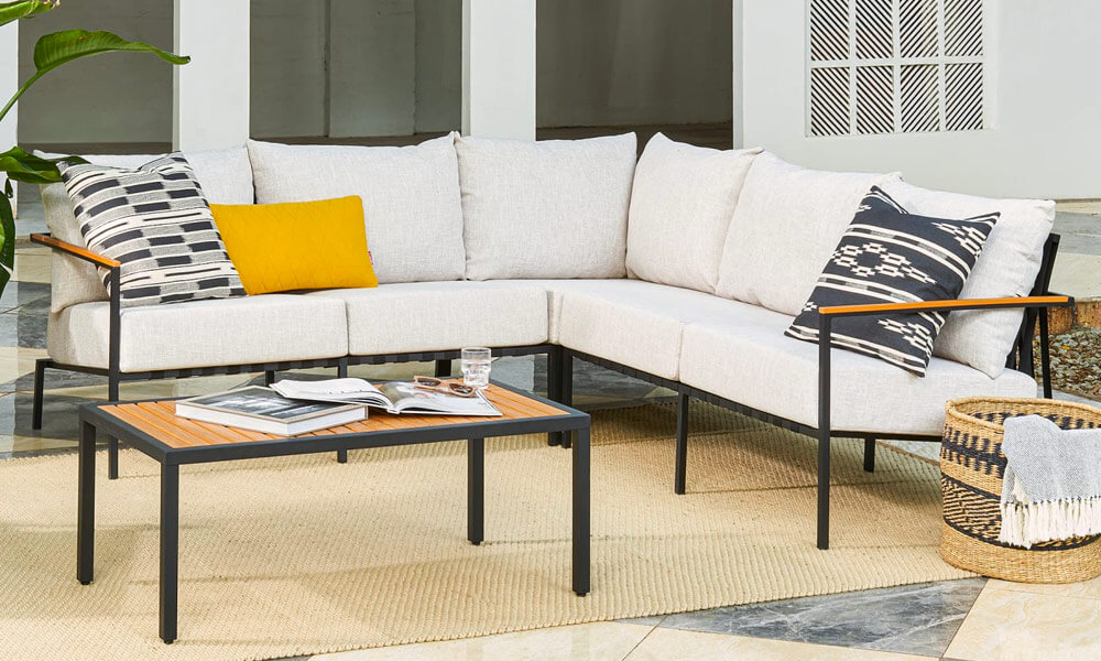 Black framed L-Shape Sectional Sofa with white cushions and a coffee table with books on it