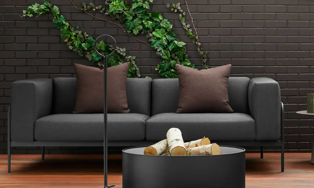 Black coffee table with fire pit, next to black sofa with brown cushions
