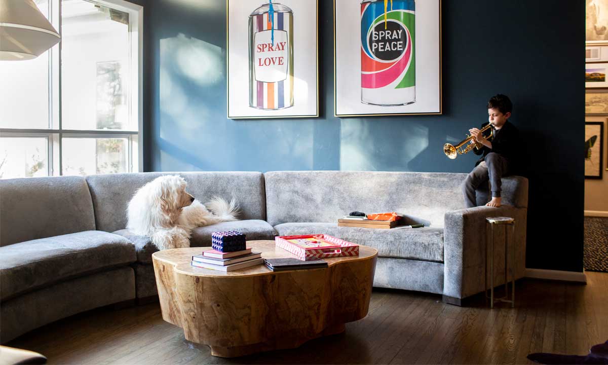 Wooden Coffee Table placed in front of a grey curved sectional with a white dog sitting on it