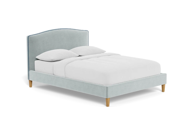 Velvet plush upholstered bed frame with a headboard, a mattress with a white cover and two pillows