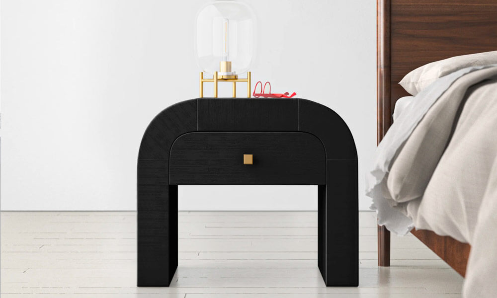 A contemporary black manufactured nightstand with a lamp on top