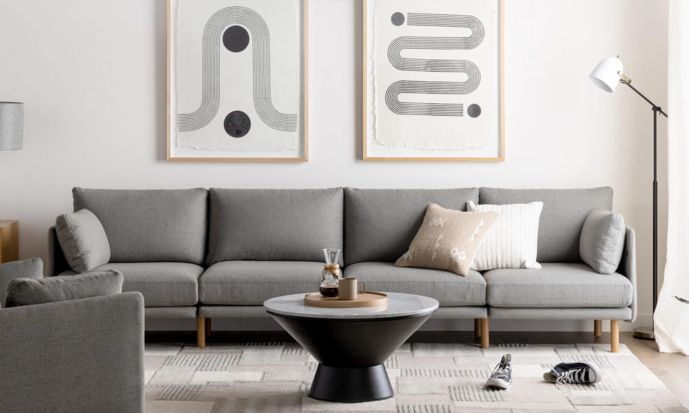 Grey upholstered sofa with wooden legs in a living space with a round black coffee table