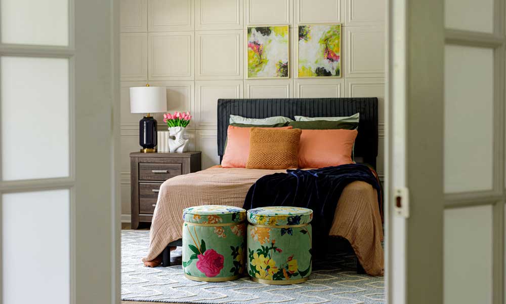 Cozy Bedroom Furniture with camel bed cover, wooden sidetable with flowers and a lamp and beige wall