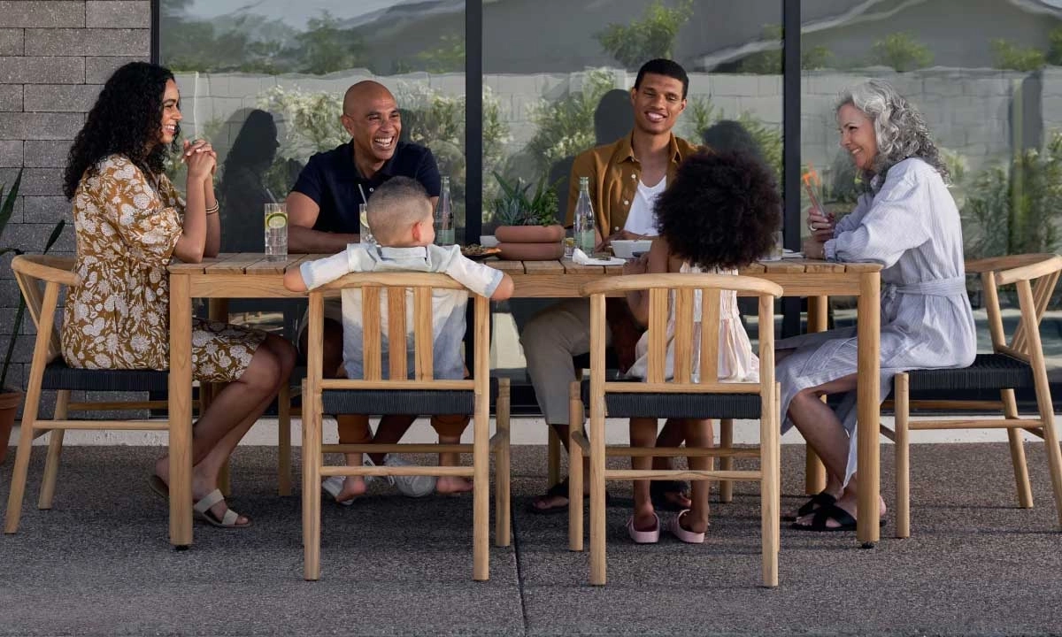 Family gathering in a wooden moodern outdoor dining set from Neighbor.