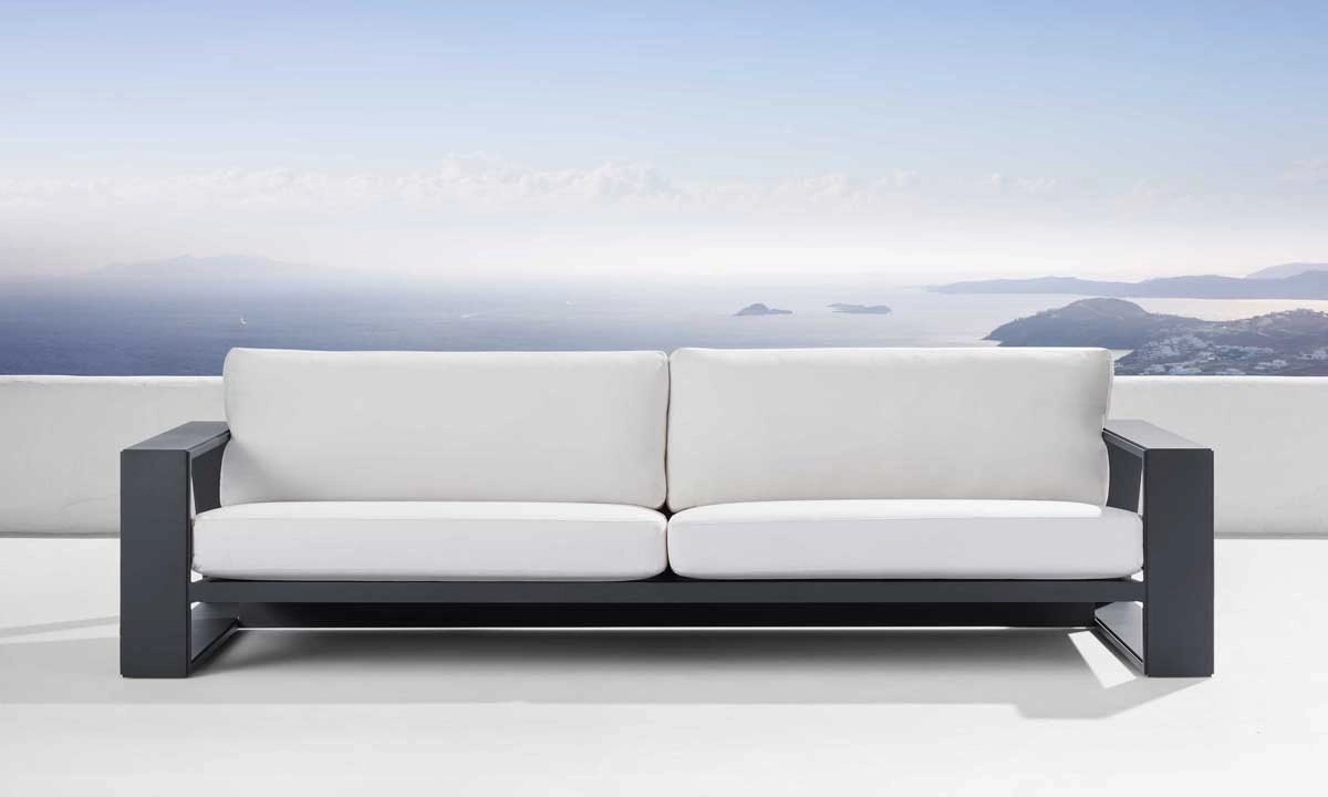 modern white sofa with dar frame on a rooftop overlooking a coastal landscape