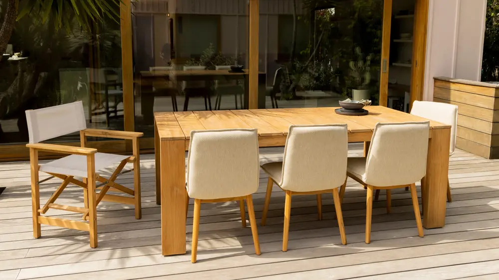 Wooden set with wooden framed chairs with beige upholstery and a sturdy wooden table in a patio