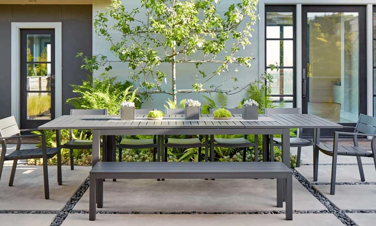 Outdoor dining area with modern gray dining table set, including hairs and a bench on a patio