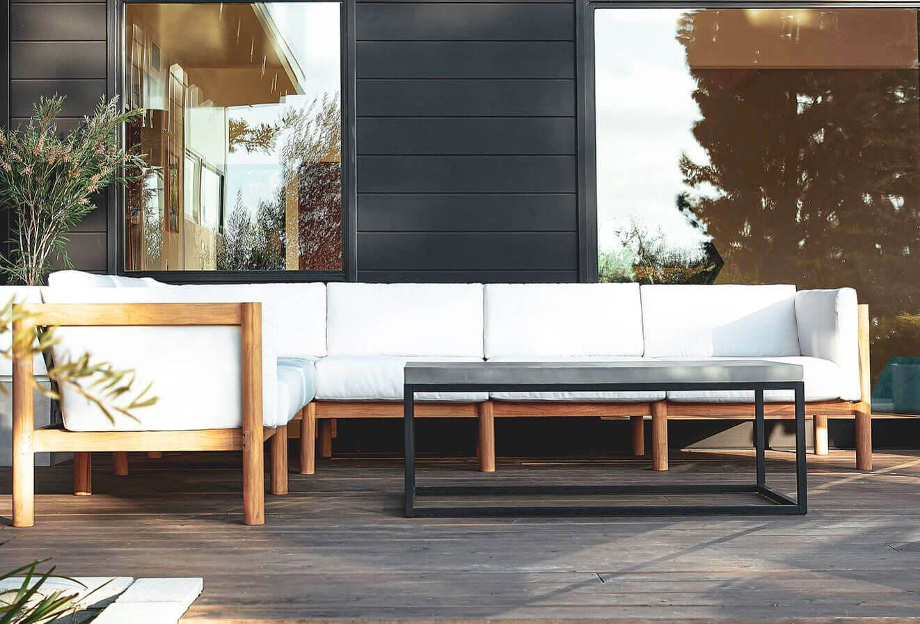 Wooden outdoor sofa with white cushions on a patio in a sunny day