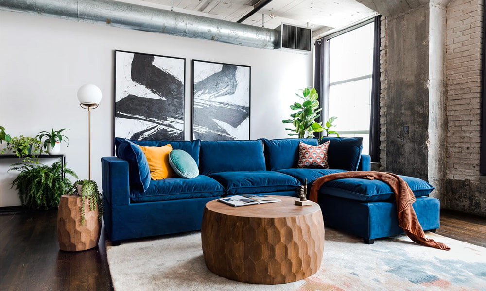 blue velvet upholstered sofa with blue, green and yellow throw pillows in a modern living room
