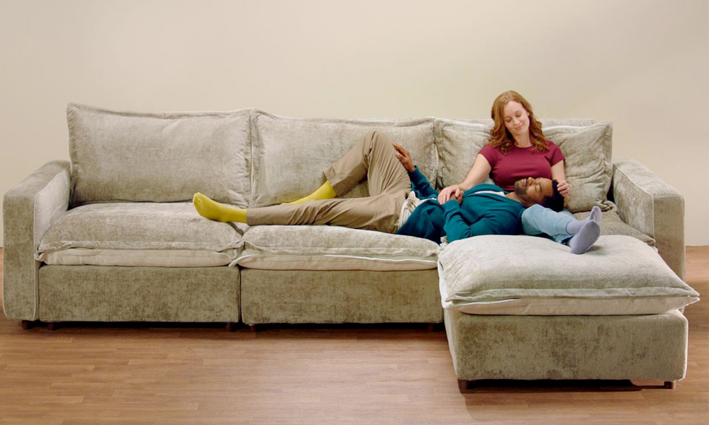 Couple sitting in a light grey couch with an ottoman