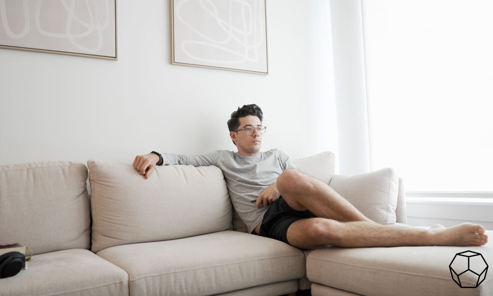 Man sitting in a Cozy beige sofa with an ottoman in a bright living room