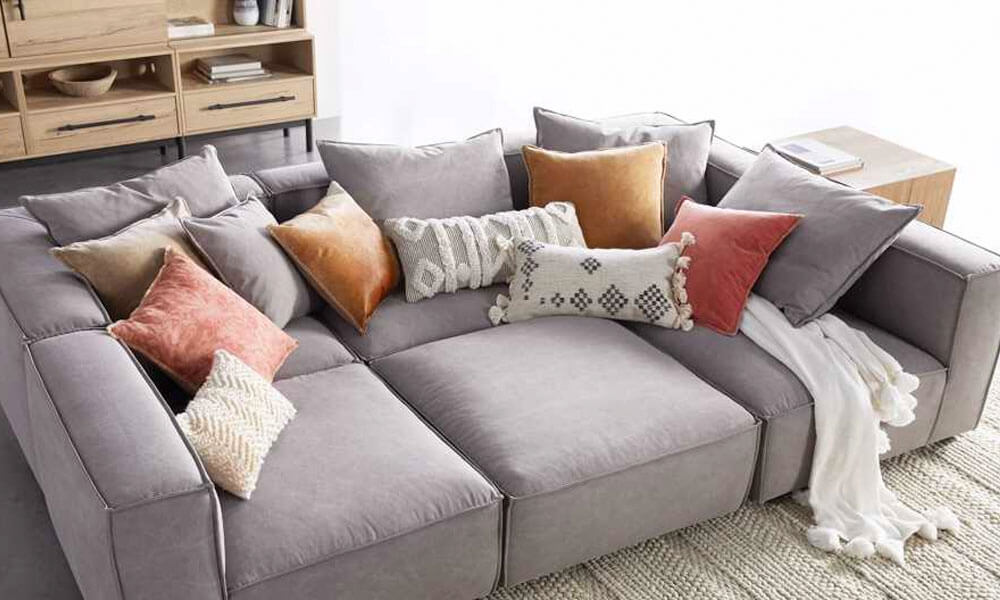 Six Piece Pit Sectional sofa with grey upholstery and a bunch of orange and grey throw pillows in it
